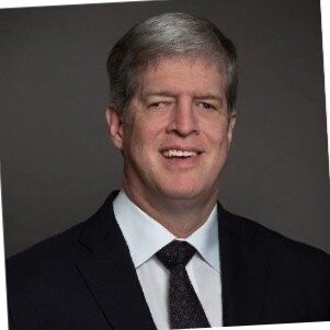 Kirk Adams headshot. Man smiling in black suit